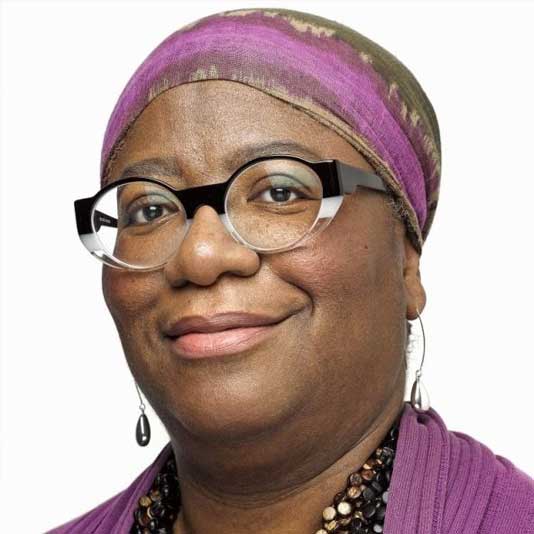 Bushra Junaid wearing glasses and a purple head wrap