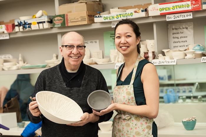 Two people holding clay bowls made on the pottery wheel