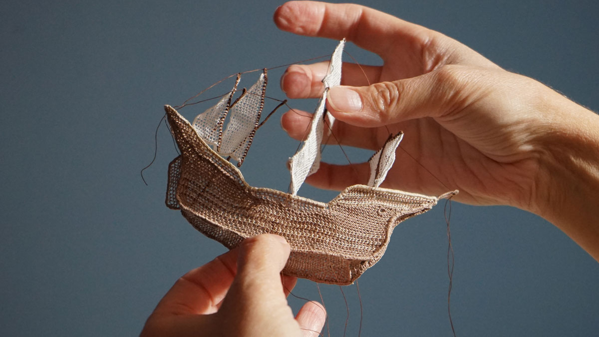 Artist Dorie Millerson holding a ship made from needle lace, cotton, and wire