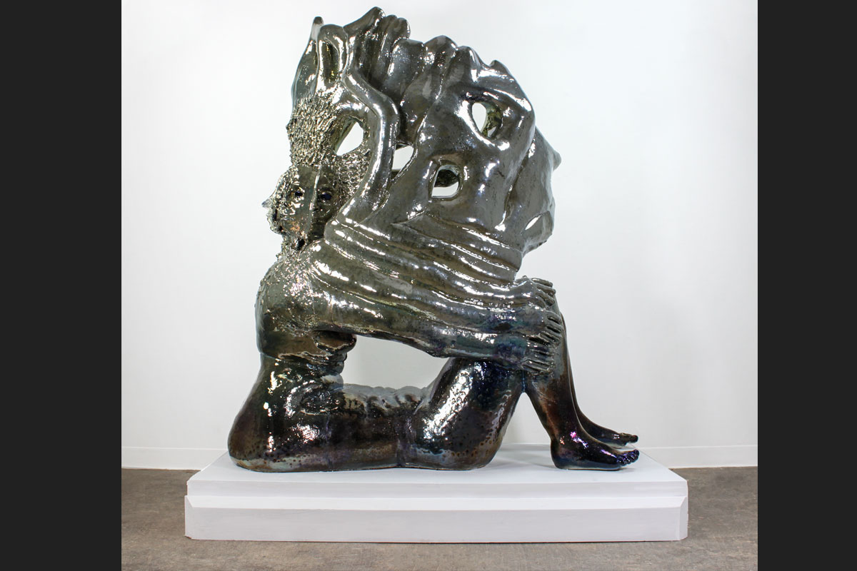 Iridescent ceramic sculpture of a seated alien figure