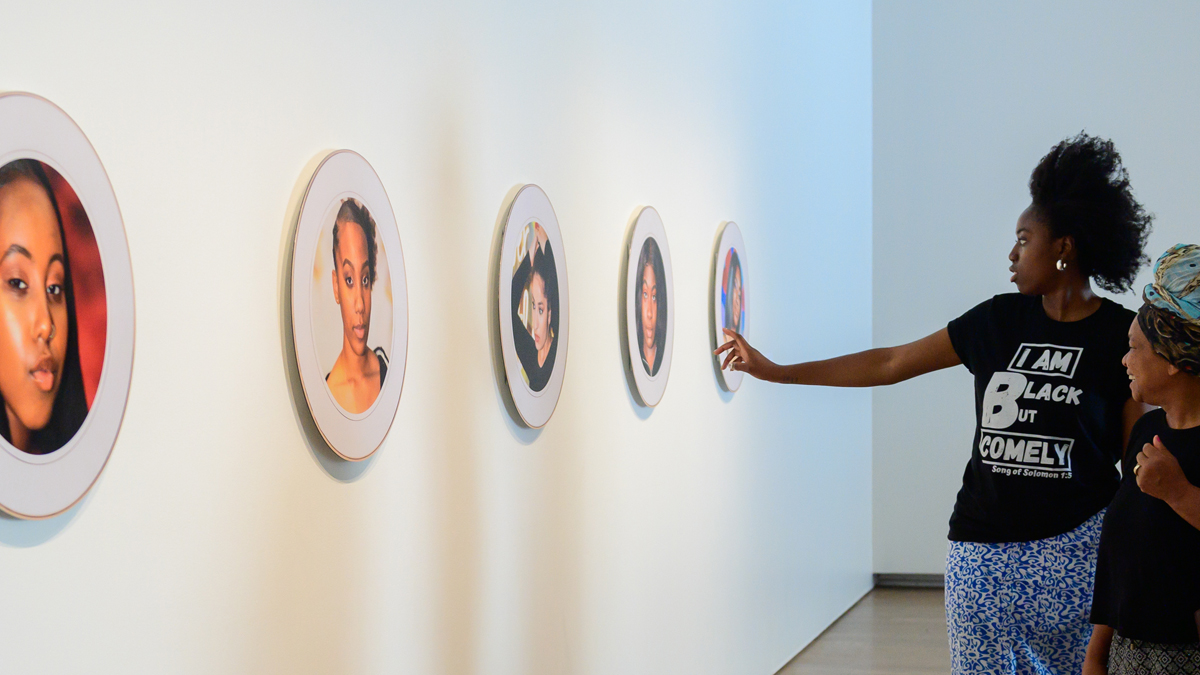 Artist Igho Diana showing visitors portraits made by youth from Art Starts