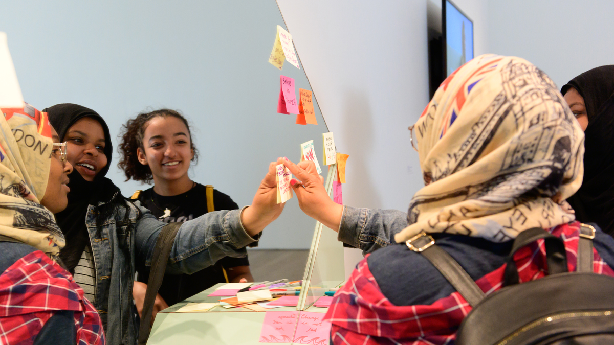 Young artists from Art Starts putting sticky notes on a mirror at the Hair We Are launch