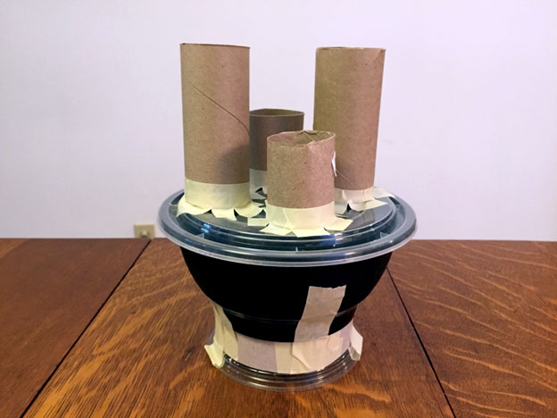 Toilet paper rolls of various heights taped to a take out container