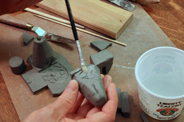 Brushing water onto a clay object