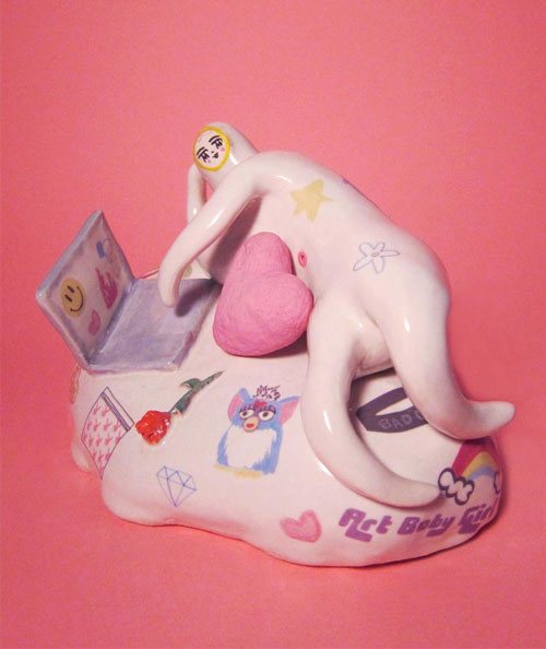 Ceramic figure on a laptop on a pink background