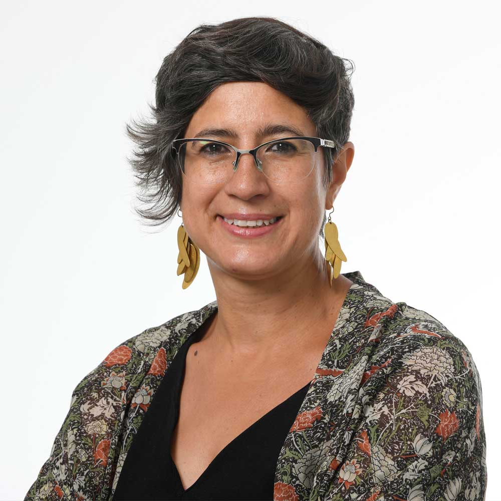 Headshot of Dr. Maria Fernanda Ugalde seen from the chest up. She is wearing a shawl, earrings, and glasses