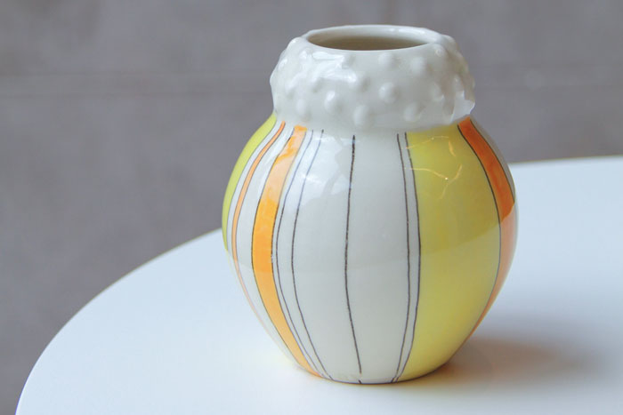 Small white ceramic vase with orange and yellow stripes