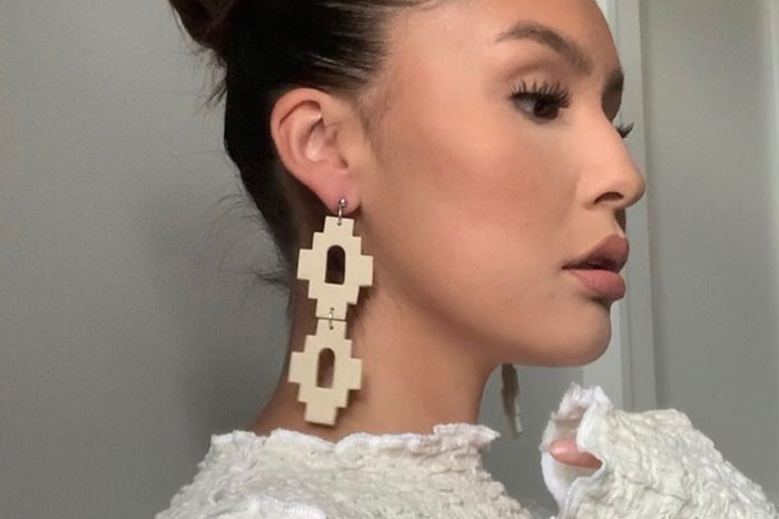 Woman wearing a pair of nude ceramicsearrings made of geometric shapes