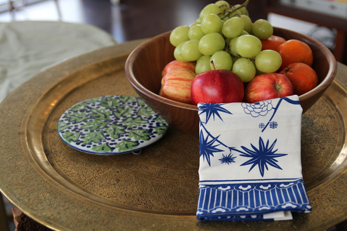 Blue and white tea towel draped over a wood bowl filled with fruit