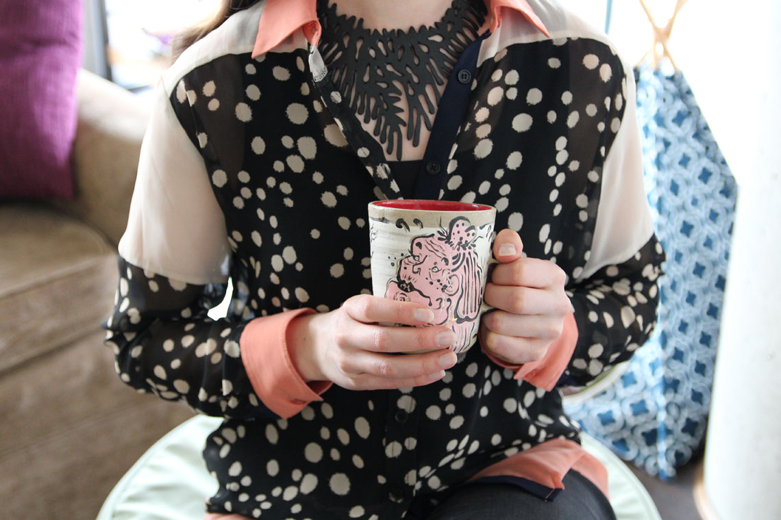 Woman wearing a polka dot shirt holding a mug