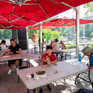People sitting at tables outside the Museum doing a clay activity