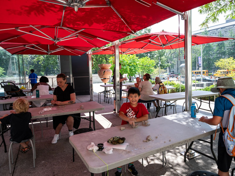 Families working with clay under red umbrellas on the Gardiner's Plaza