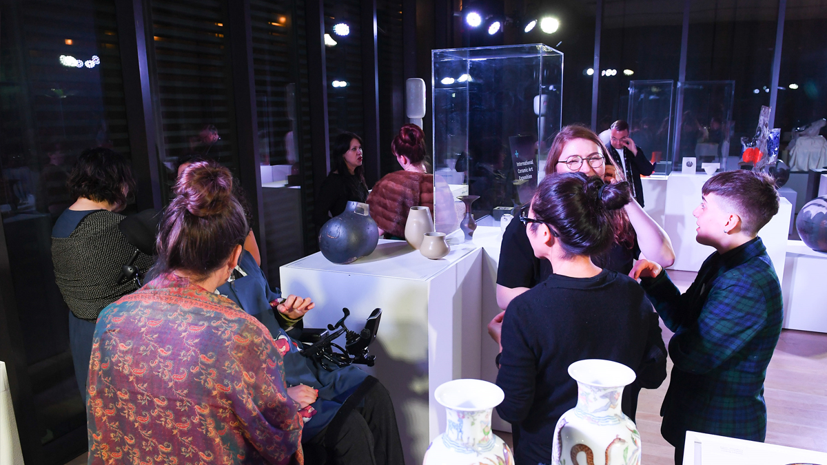 Guests talking surrounding by art in cases at the annual fundraising gala