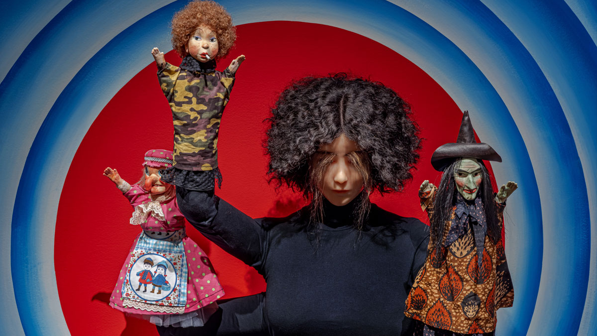 Sculpture of a female figure holding three puppets
