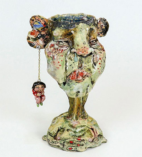 eramic bust with smaller ceramic figure dangling from its ear