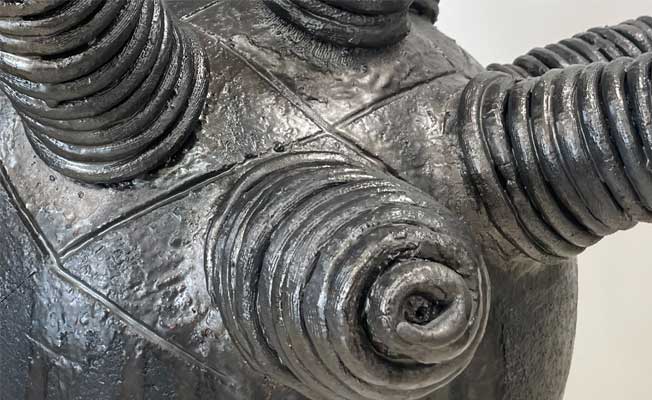 A black ceramic sculpture with coiled protrusions sticking out of it