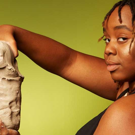 Shannon Weston holding a block of clay against a green background