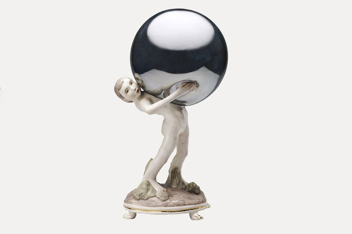 Ceramic figure of a boy holding a mirrored globe