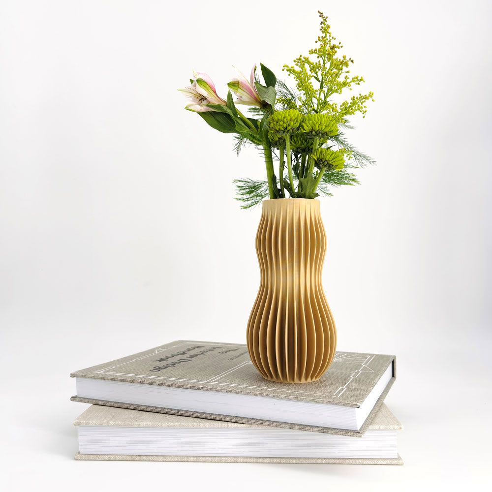 A yellow ribbed vase on a stack of books