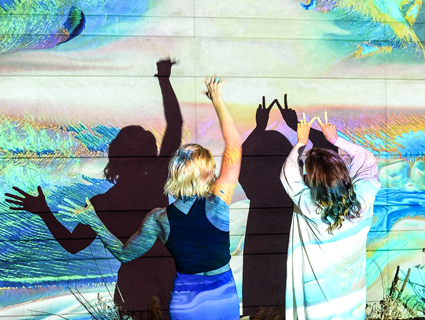 Two people dancing in front of an art projection