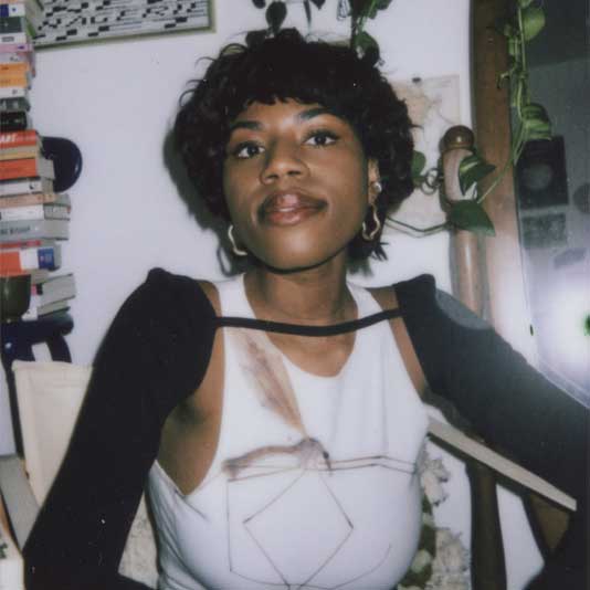 Artist Zainab Aliyu in a white tank top and black sweater